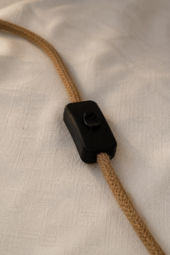 Interrupteur noir et câble textile beige de la lampe en bois flotté.